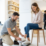 Professional shoe fitter measuring customer foot with Brannock device