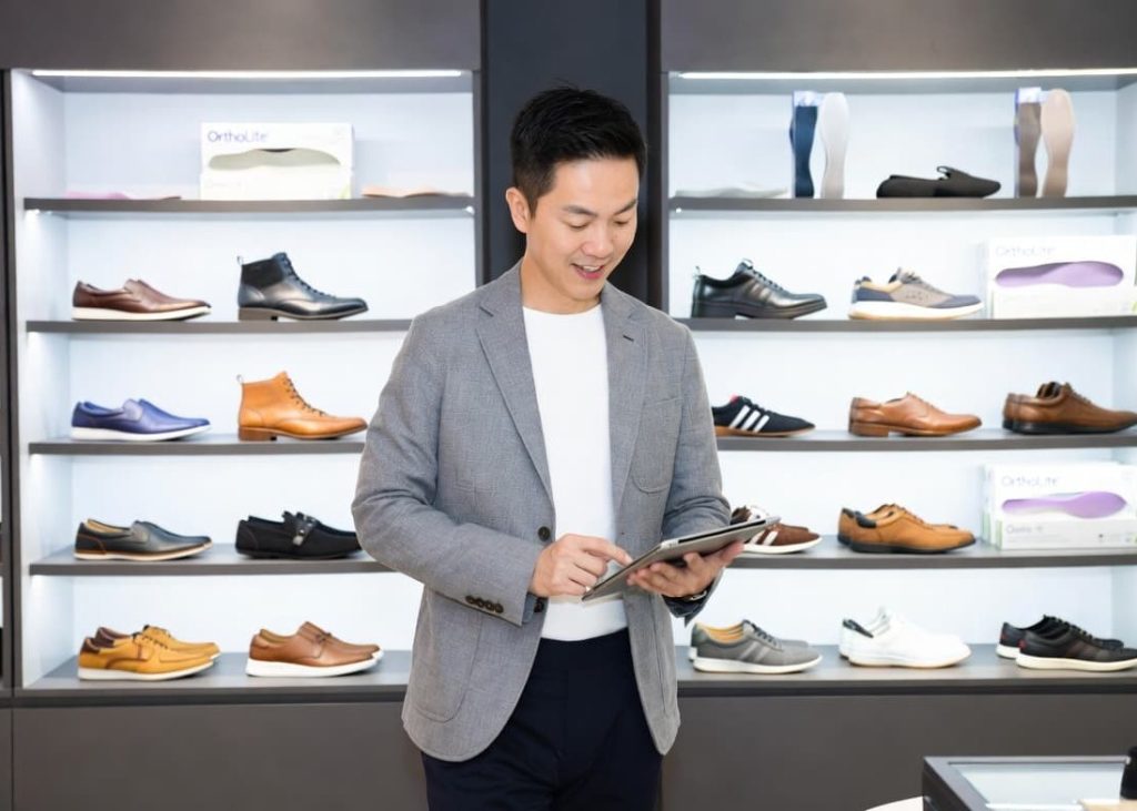 Corporate executive analyzing global footwear supply metrics on a digital tablet within a modern corporate product showroom.