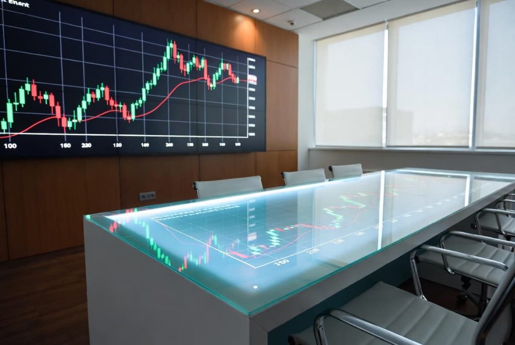 A modern executive boardroom table displaying reflective stock market data metrics and financial trend graphs.