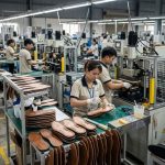 Footwear operators performing outsole stock fitting assembly in a modern footwear manufacturing factory.